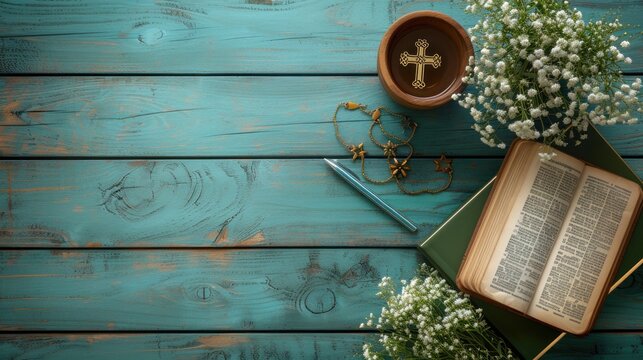 an open book with a cross on top of it next to a vase of flowers and a knife on a blue wooden table.
