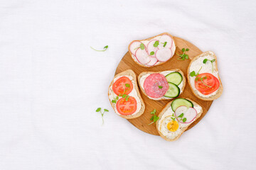 Different tapsas sandwiches with vegetables on board on white background. top view.