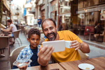 Man and boy taking a selfie at an outdoor cafe