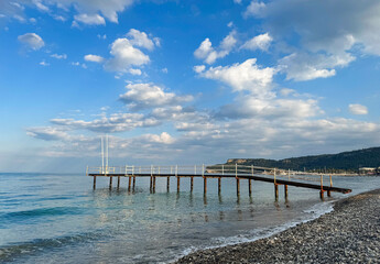 Seascape, landscape on a sunny summer cloudless day, pier. Calm sea, mountains and pebble beach, Turkey, Antalya, Kemer.