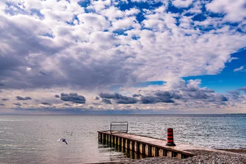 Fotobehang dramatic clouds over a storm sewer outflow and lake ontario seen from balmy beach in toronto beaches neighbourhood room for text © Michael Connor Photo