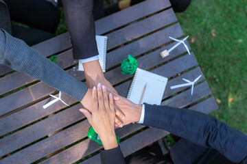 Business people join hand together as teamwork and unity, outdoor business meeting table. Eco-friendly practices and collaboration in corporate social responsibility for greener environment. Gyre