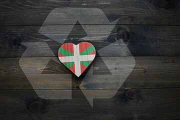 wooden heart with national flag of basque country near reduce, reuse and recycle sing on the wooden...