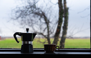 Cup of coffee and Italian coffee pot on a window on a rainy day