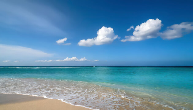 A beautiful beach with a blue ocean and white clouds in the sky. The ocean is calm and the waves are small. The beach is empty and peaceful