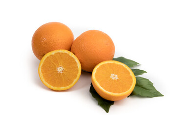 two ripe oranges and a cut orange on a green leaf isolated on white