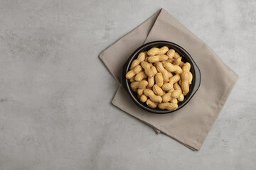 Peanut in a bowl on play stone background top view copy space. Healthy snack food.