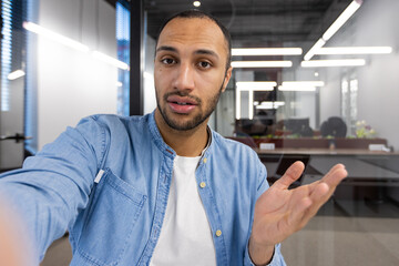 A man with a beard and a blue shirt is looking at the camera