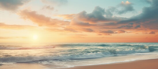 Naklejka na ściany i meble Sunset over the ocean with waves crashing on the beach
