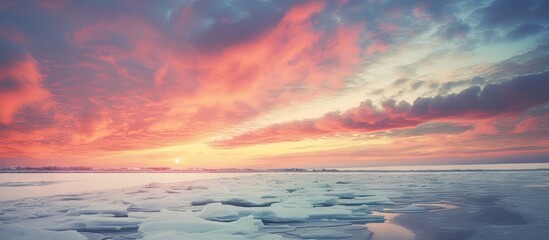 Fototapeta premium Cloudy sky over icy shore with bright winter sunset