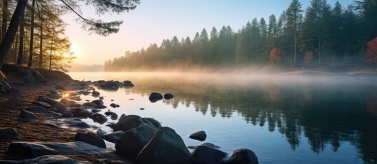 Morning sunrise over calm lake with trees and rocks