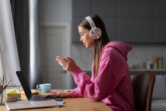 Teen schoolgirl in headphones studying online with remote tutor from home, student using laptop talking in webcam video chat learning lesson with distance teacher