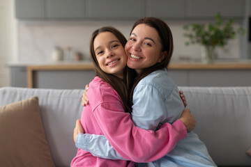 Loving mother hugging embracing her happy teen daughter at home, expressing love to teenage child,...