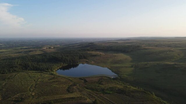 A drone shot of a beautiful small lake in the green mountains on a summer day at Bragan Mountains, Co. Monaghan, Ireland