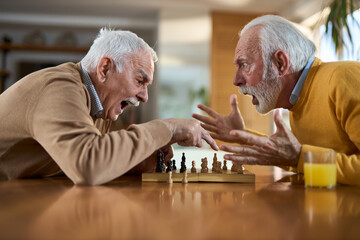 Senior man arguing while playing chess at home