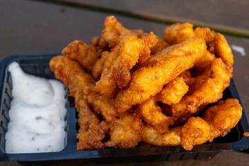 Outdoor eating of diep-fried cod fish pieces served with remoulade sauce, Dutch street food