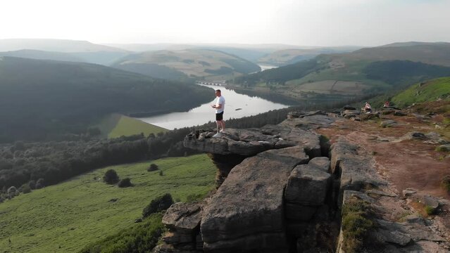 Young man standing on the edge of rocks at Bamford Edge in the Peak District National Park