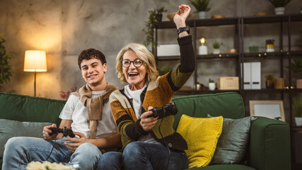 teenager male and his mother mature woman man play console video game