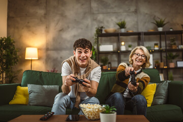 teenager male and his mother mature woman man play console video game