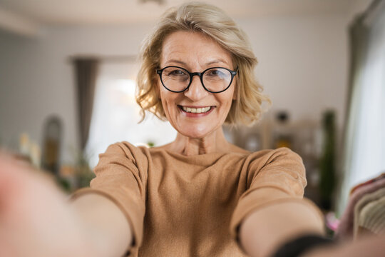 Portrait of one mature blonde caucasian woman with eyeglasses at home