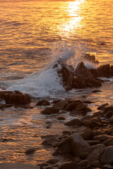 Beach waves at sunrise sunset over rocks on the coastline beach