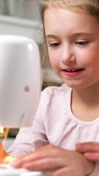 Mother teaching her little daughter to sew using a sewing machine in the nursery at home. Children's craft, education and training. Vertical video for smartphone screen, for target social media