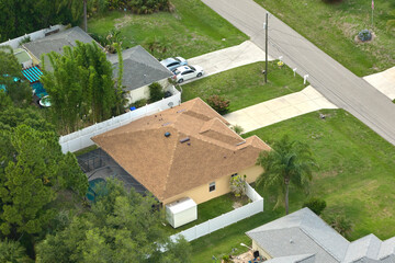 Aerial view of typical contemporary american private house with roof top covered with asphalt shingles and green lawn on yard
