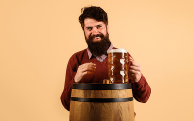Beer time. Bearded man with mug of beer on wooden barrel. Smiling handsome male drinking beer. Germany traditions. Oktoberfest festival. Beer pub and bar. Holiday, drinks, alcohol and leisure concept.