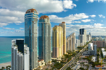 View from above of luxurious highrise hotels and condos on Atlantic ocean shore in Sunny Isles Beach city. Urban street with busy traffic. American tourism infrastructure in southern Florida