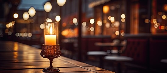 Candles are illuminated on a rustic wooden table placed inside a cozy restaurant setting - obrazy, fototapety, plakaty