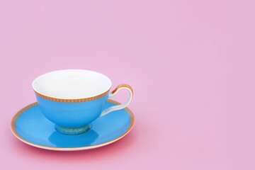 Blue and gold bone china tea cup. Elegant luxury drinking set on pastel pink background with copy space.