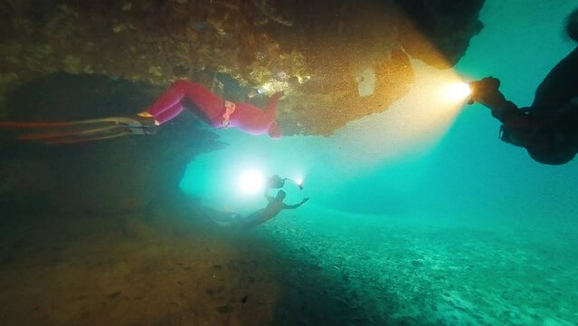 Cave freediving. Freedivers dive inside the cave with underwater camera and explore the intricate seascape of West Papua region, Indonesia