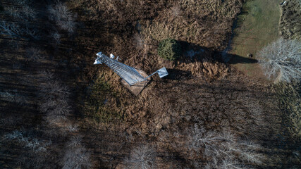 Aerial view looking down at a Communication Tower with satellite dishes on a field in the forest