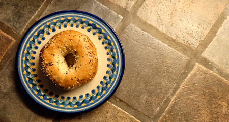 everything bagel on a painted plate on a rustic porcelain tiled countertop - diamond background
