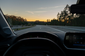 Fototapeta na wymiar View from inside the car to highway with sunset in the background. Night fall view from Driver POV to the road landscape.