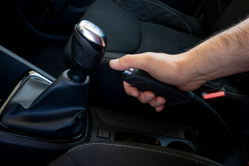 Close up of a man's hand tightens the manual handbrake on the car