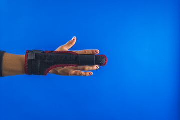 Plastic two sided finger splint with two convenient hook and loop straps on an broken middle finger, blue backgroud. High quality photo