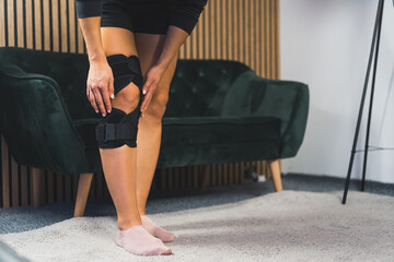 Photo of women leg in knee brace at home, injuries and pain. High quality photo
