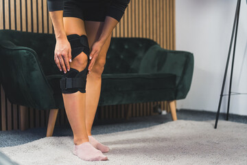 Photo of women leg in knee brace at home, injuries and pain. High quality photo