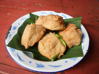 Deep fried stuffed tofu white chopped mix vegetables or called Tahu Isi traditional popular snack food isolated on wooden table background