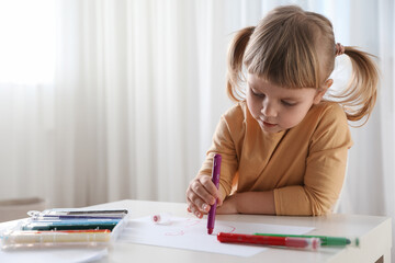 Naklejka premium Cute little girl drawing with marker at white table indoors. Child`s art