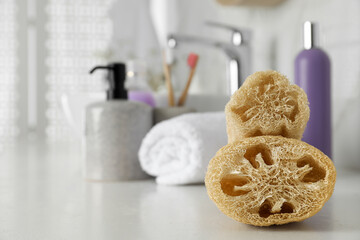 Fototapeta na wymiar Natural loofah sponges on table in bathroom. Space for text