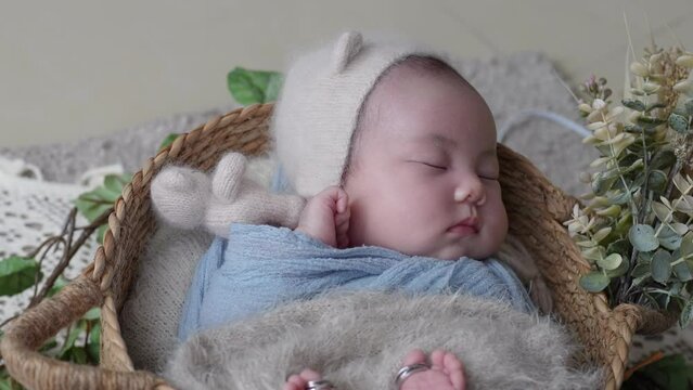 A 32-day-old Taiwanese baby wrapped in a blue wrap and taking a newborn photogorahy 生後32日の台湾人の赤ちゃんが青いおくるみを巻かれて、ニューボーンフォトを撮影されている様子