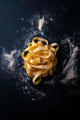 Swirl of fettuccine pasta elegantly suspended in mid-air with a sprinkle of flour, capturing the essence of Italian cuisine and the art of pasta making.

