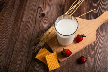 Fototapeta na wymiar Glass of milk, cookies and strawberries on wooden table, Breakfast concept.