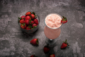 Strawberry milkshake on cement table with dark background. Strawberry frappe.