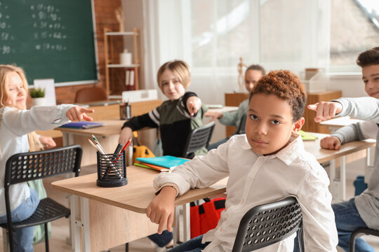 Bullied little African-American boy sitting in classroom
