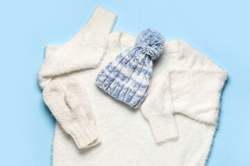 Warm female sweater, hat and mittens on color background