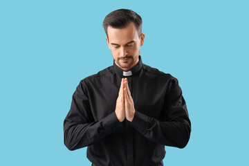 Portrait of male priest praying on blue background