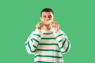 Young man with pomelo piece on green background